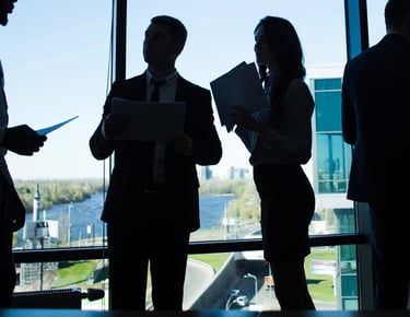 a group of people standing in front of a window discussing solution for client