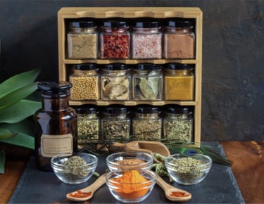 A wooden spice rack with glass jars containing colorful dried herbs and spices for kitchen organization.