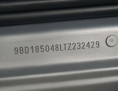 Número de chassi gravado na lataria metálica de carro usado durante vistoria automotiva.