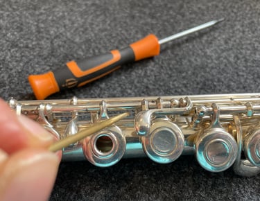 gros plan sur une main tenant un outils pour entretenir une flûte traversière