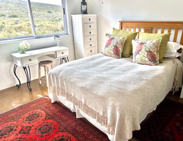  Reubens Choice bedroom decor featuring a wooden bed and a red Persian rug with a window view.