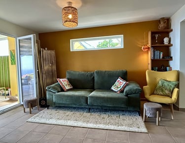 Bohemian living room with a green velvet sofa, mustard yellow accent wall, and woven pendant light.