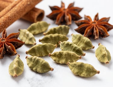 Close-up macro shot of whole green cardamom pods, star anise, and cinnamon sticks scattered on a clean white marble surface, bright natural daylight