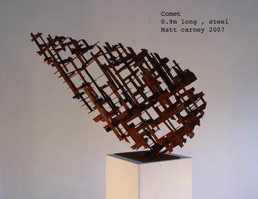 a rusted steel cross-hatched comet shaped sculpture