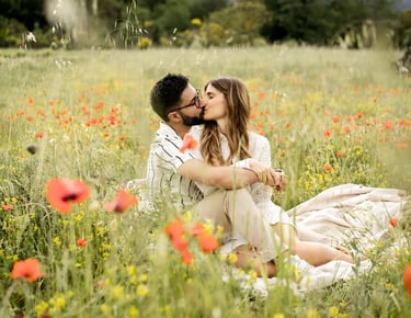 Editorial engagement photo of a couple kissing in a Provence poppy field by a fine art photographer