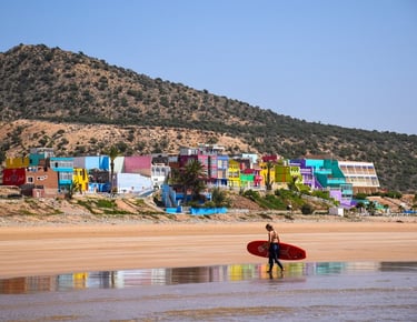 a person holding a surfboard while walking on the beach