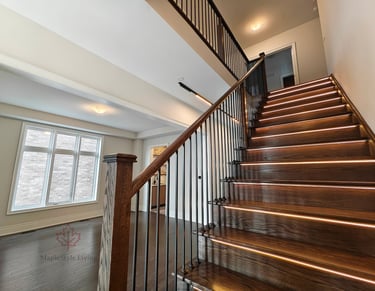 Architectural oak staircase with modern black railings and integrated linear step lighting in a high