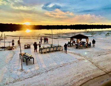 Jantar servido em uma praia de rio com o por do sol