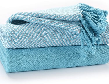 Stacked turquoise cotton throw blankets with white herringbone pattern and fringed edges.