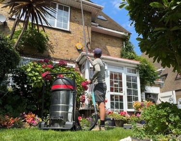 front of the house where a man holds a long pole while cleaning a gutter