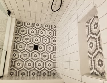 Modern walk-in shower featuring gray and white geometric hexagon floor tile and white vertical subway wall tile.