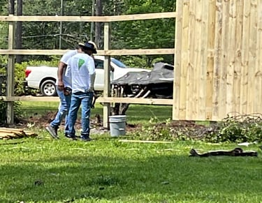 man working carpentry on wooden fence wearing garnetpainti remodeling company shirts