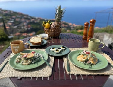 Gourmet breakfast on a patio with a sea view, featuring deviled eggs with caviar, salad, and coffee.