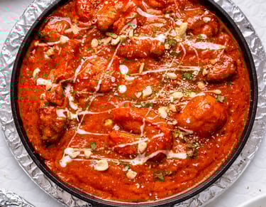 Spicy Indian butter chicken or shrimp tikka masala in a cast iron skillet with cream and nuts.