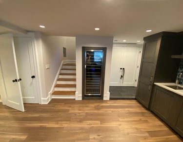 The remodeled basement featuring a built-in wine cooler, hardwood floors and dark kitchen cabinetry.