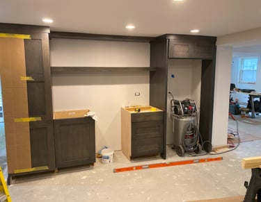Basement remodel in progress featuring dark gray custom cabinetry and built-in shelving.