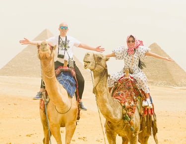 A couple riding a camel in front of the pyramids in Egypt