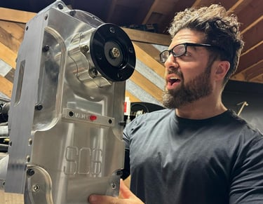 don abenante holding a high-performance SCS gear drive transfer case in a workshop.