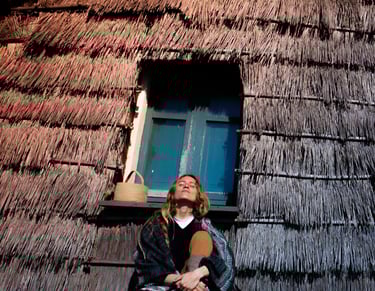 a woman sitting in front of ancient sardinian house on the seaside