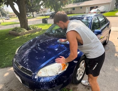 Golden mobile detailing team giving a blue sedan an exterior wash