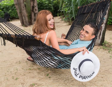 A joyful newlywed couple lounging in a black hammock on a sandy tropical beach in Koh Samui