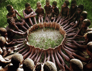 grupo de niños africanos con una escucha activasentados en el suelo creando un circulo con los pies 