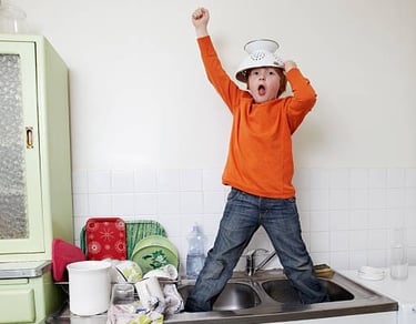 a young boy standing in a kitchen sink