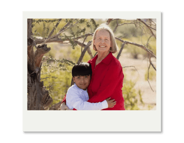 Smiling grandmother and grandson hugging outdoors in a sunny park landscape.