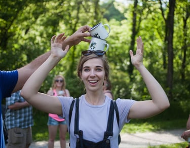 Woman balancing 2 Greenbelt stamped mugs on her head