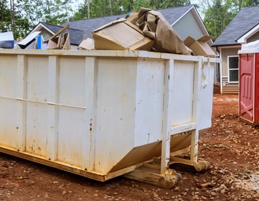 alt="Residential junk removal dumpster positioned in driveway for hauling furniture and debris"
