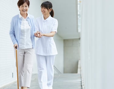 une femme âgée s'appuyant sur sa canne aidé d'une soignante esquifs quelques pas.