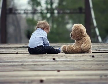 a little boy sitting on a wooden bridge