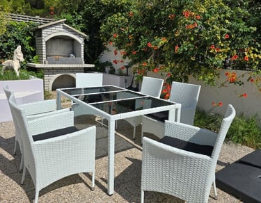 The photograph shows a dining set in the courtyard of Lokva Rogoznica's house and a barbecue.