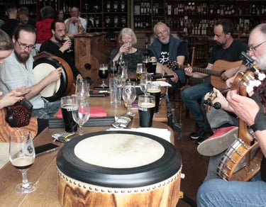 Musicians playing traditional Irish instruments and drinking Guinness during a live pub session.