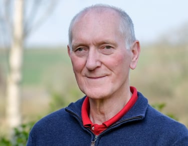 Portrait of white man with grey hair and blue jumper