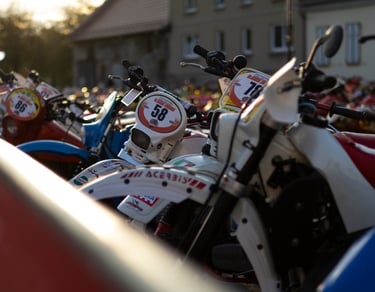 Close-up of vintage enduro motorcycles lined up for a classic off-road race at sunset.