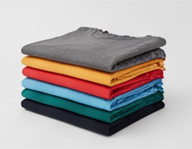A stack of neatly folded t-shirts in vibrant rainbow colors, showing a variety of hues from gray and red to blue and black.