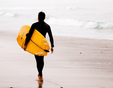 a man in a wetsuit is holding a surfboard