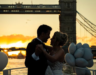 bride and groom kissing on a boat with Tower Bridge, London in their background