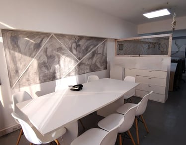 Sala de firmas en Red de Llaves, con mesa blanca, sillas modernas y luz natural por ventanales.