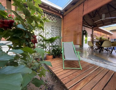 A green striped deck chair sits on a wooden patio in a tropical garden patio setting.