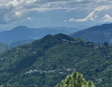 View of beautiful mountain ranges in Himachal Pradesh  with small groups of houses in the distance.
