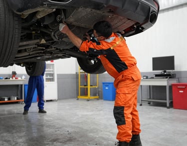 Mechanic inspecting a car engine in a modern workshop with orange and black accents.