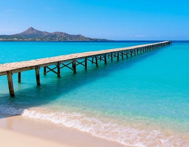Playa de Muro en Mallorca con muelle de madera sobre aguas turquesas y montañas al fondo – Maiorca Unlocked.