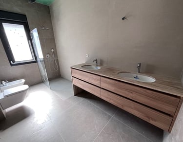 Salle de bains moderne avec double vasque en bois, murs en carrelage effet pierre, douche à l’italie