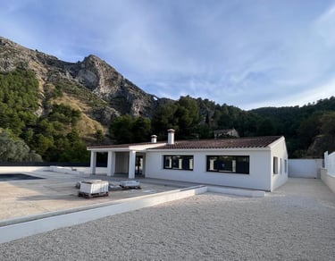 Villa moderne blanche avec toit en terre cuite, nichée au cœur de montagnes pittoresques