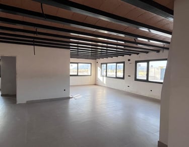 Pièce moderne en open space en cours de construction, avec poutres métalliques apparentes au plafond