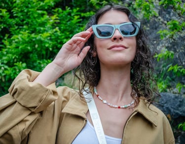Woman outside looking up and touching her eco-conscious sunglasses