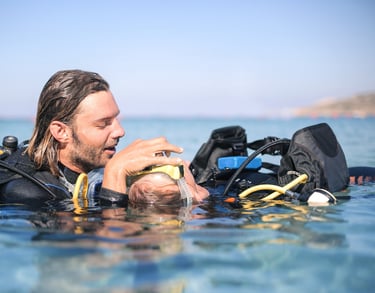 a man in a wetsuit is holding a baby in the water