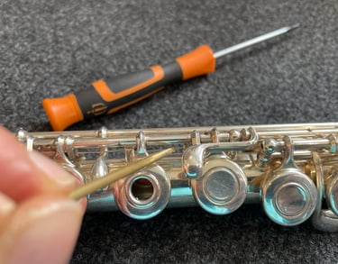 gros plan sur une main tenant un outils pour entretenir une flûte traversière